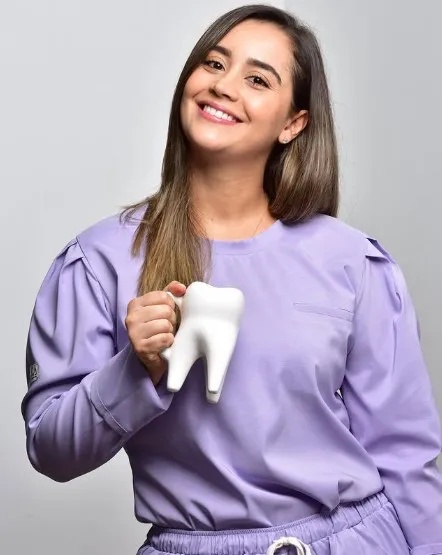 Dra. Pilar Milanés implant dentist and oral rehabilitation specialist holding a coffee cup in a shape of a tooth in her clinic in Cali Colombia
